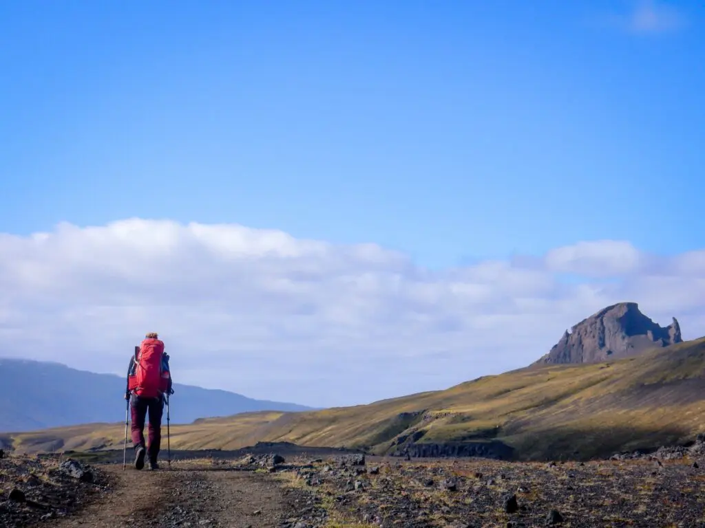 hiker with red backpack on a trail in icelandic landscape