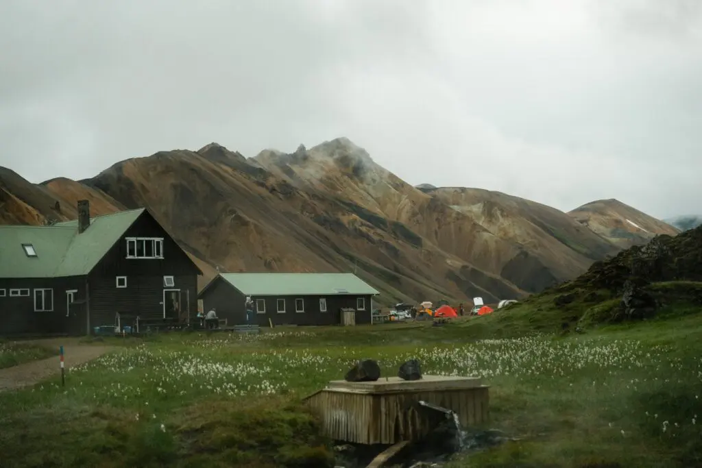 mountain huts and tents in a valley with geothermal spring